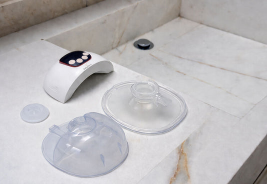 Wearable breast pump components including motor, flange, and milk collector placed on countertop