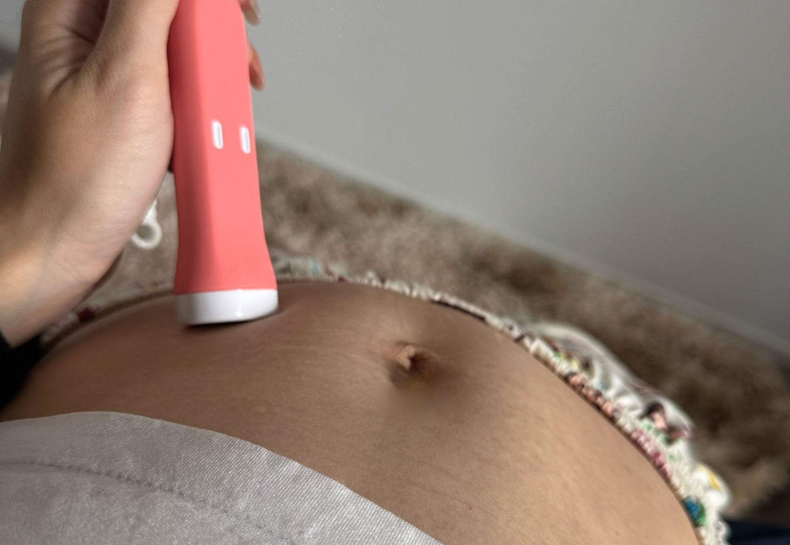 pregnant woman using fetal doppler on belly at home to check baby heartbeat