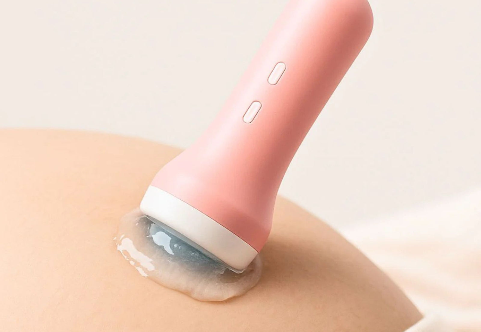 Close-up of a pink fetal doppler probe placed on a pregnant belly with gel, showing correct positioning for detecting baby’s heartbeat.