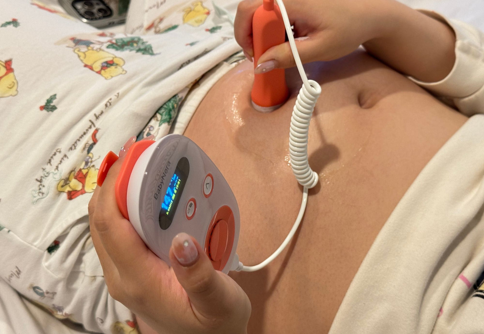 Pregnant mother using BabyNera home fetal doppler on her belly to monitor baby heartbeat during pregnancy at home.