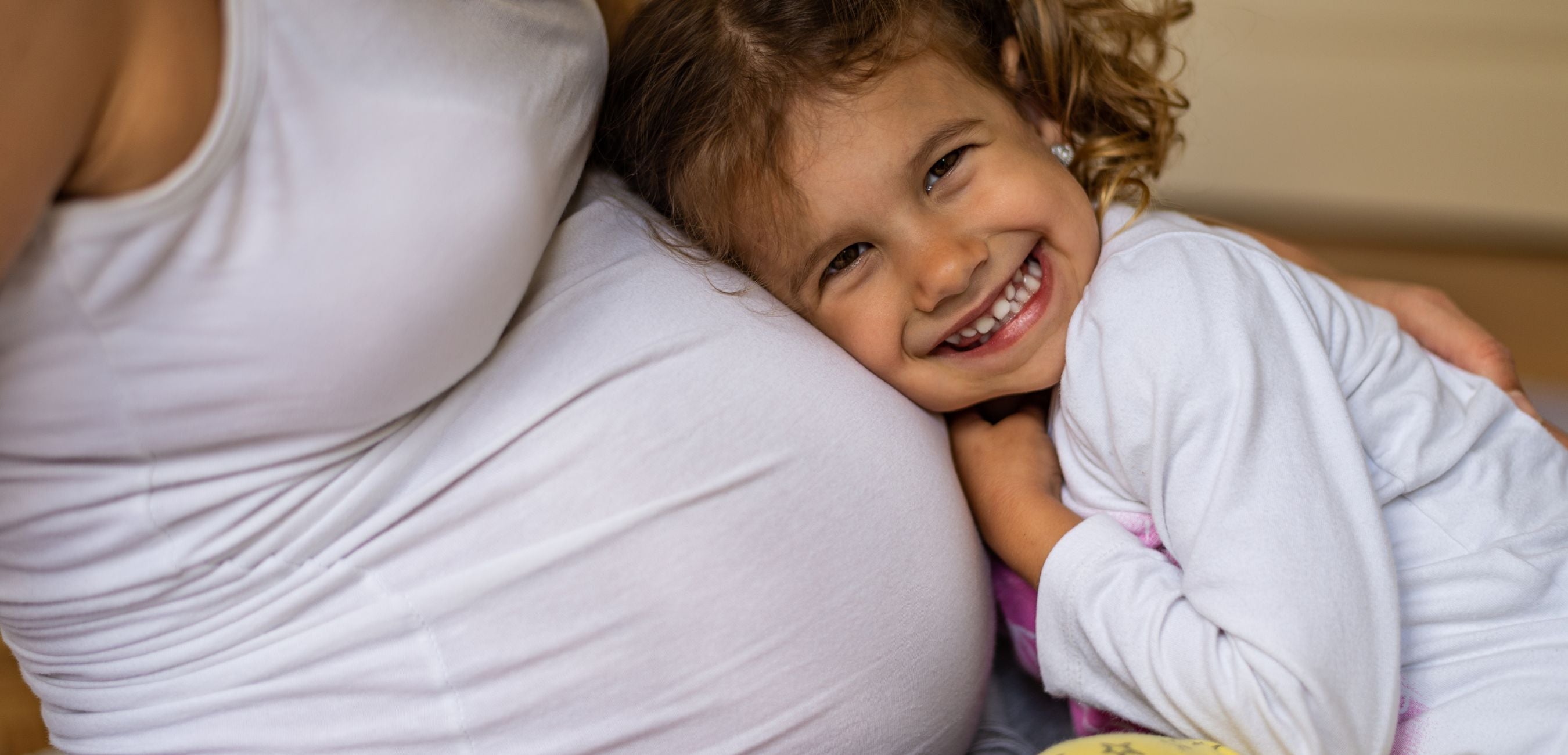 Young child hugging a pregnant mother’s belly during a family bonding moment at home during pregnancy